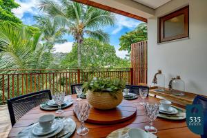 une salle à manger avec une table et un balcon avec des palmiers dans l'établissement Conforto e comodidade em Praia do Forte, à Mata de São João