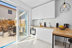 a kitchen with white cabinets and a dining table at Apartment Sunshine Cres in Cres