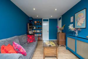 uma sala de estar com paredes azuis e um sofá cinzento em ALTIDO Striking flat with charming garden em Londres