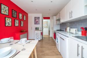 uma cozinha com paredes vermelhas e uma mesa com copos de vinho em ALTIDO Striking flat with charming garden em Londres