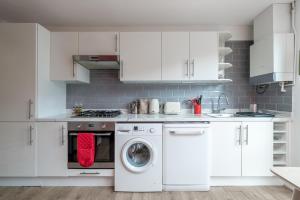 a kitchen with white cabinets and a washing machine at ALTIDO Striking flat with charming garden in London