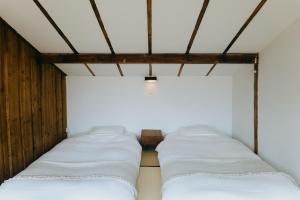 uma fila de camas num quarto com lençóis brancos em Hostel Saruya em Fujiyoshida