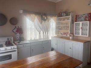 a kitchen with white cabinets and a wooden table at JanRI Gasteplaas in Strydenburg