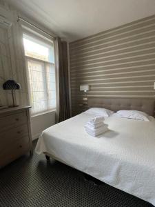 sypialnia z białym łóżkiem i ręcznikami w obiekcie Le Pavillon d'Enghien, Vichy Centre w mieście Vichy