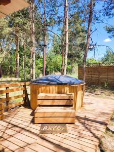 une terrasse en bois avec un bain à remous et des bancs dans l'établissement Domki SHERWOOD, 