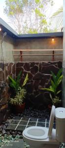 a bathroom with a stone wall and a toilet and plants at Mengalung Bungalow in Kuta Lombok