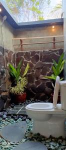 a bathroom with a toilet in front of a stone wall at Mengalung Bungalow in Kuta Lombok