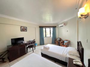 una camera da letto con un letto e una scrivania con una televisione di ēRYA by SURIA Cherating a Cherating