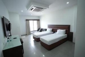 a hotel room with two beds and a flat screen tv at Hotel Metropolis in Hubli