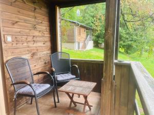 2 Stühle und ein Tisch auf einer Veranda mit einem Fenster in der Unterkunft Chata Adam u Lipna in Horní Planá