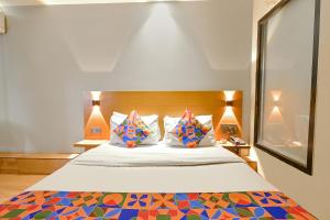 a bedroom with a large bed with colorful sheets and pillows at FabHotel Penthouse in Guwahati