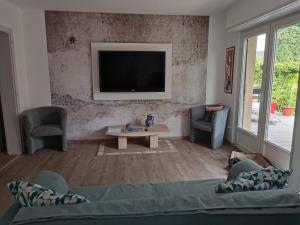 uma sala de estar com um sofá e uma televisão na parede em Villa de plain-pied au calme em Mundolsheim