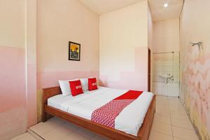 a bedroom with a bed with red pillows and a shower at Super OYO 3693 Kopi Klotok Homestay Syariah in Magelang