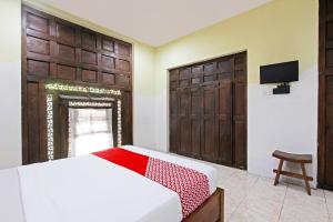 een slaapkamer met een bed en een tv aan de muur bij Super OYO 3693 Kopi Klotok Homestay Syariah in Magelang