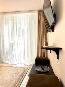 a living room with a large window with a television at Scandinavia Apartament in Piatra Neamţ