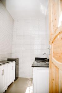 a kitchen with a sink and a white tiled wall at ESN LODGES & HOMETSAY SERVICES in Dar es Salaam