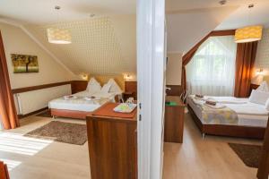 Un dormitorio con 2 camas y un escritorio en una habitación. en Hotel Pávai en Hajdúszoboszló
