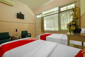 a bedroom with two beds and a tv and a window at OYO 92454 Griya Raharja Guest House Syariah in Klaten