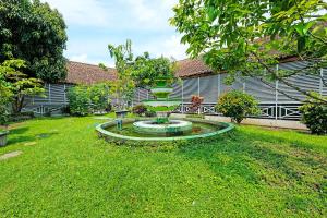a garden with a fountain in the middle of a yard at OYO 92454 Griya Raharja Guest House Syariah in Klaten