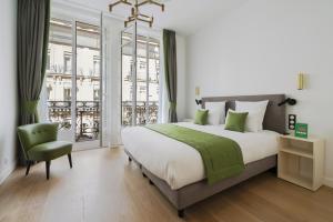 - une chambre avec un grand lit et une chaise verte dans l'établissement Vestay Montaigne, à Paris