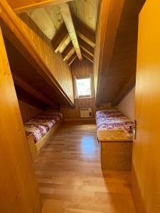ポッツァ・ディ・ファッサにあるAppartamento Monzoniのベッド2台と窓が備わる屋根裏部屋です。