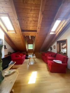 a living room with red furniture and wooden ceilings at Appartamento Monzoni in Pozza di Fassa