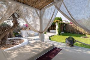 a patio with a white canopy and a garden at Elefteria Apts & Suites in Kolimbia