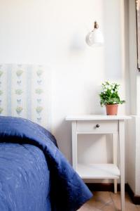 a bed with a blue comforter and a white night stand with a plant at Borgo San Valentino in Arrone