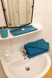 um lavatório de casa de banho com espelho e toalhas azuis em Tauglerei Doppelzimmer Bergamotte em Sankt Koloman