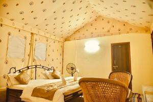 a bedroom with a bed and chairs in a room at Destination Desert Camp in Jaisalmer