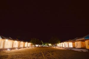una calle vacía por la noche con edificios y árboles en Destination Desert Camp en Jaisalmer