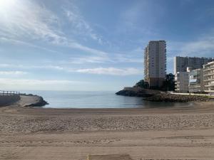 a beach with a tall building and the ocean at El Faro - Beach in Cullera