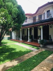 a house with a porch and a grass yard at Kavee Transit Hotel in Katunayaka