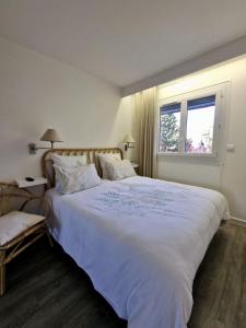 sypialnia z dużym białym łóżkiem i oknem w obiekcie Charmant 2 pièces à deux pas de la mer w mieście Cabourg