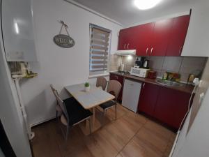 een kleine keuken met een tafel en rode kasten bij Apartament Claudia in Deva