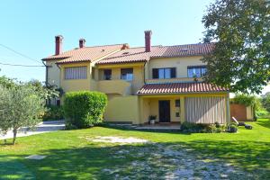 duży żółty dom z zielonym dziedzińcem w obiekcie House Slavko 2297 w mieście Grandići
