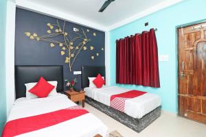 duas camas num quarto com paredes azuis e cortinas vermelhas em OYO Flagship Fun Friday Guesthouse em Bodh Gaya