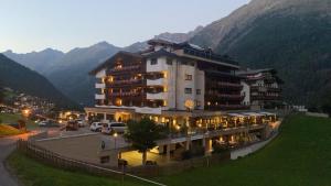 a large building on a hill with mountains in the background at Appartements Belledonne Ski & Bike in and out, zentrale Lage in Sölden