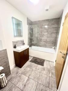 bagno con vasca, lavandino e doccia di Home from Homes a Bedford