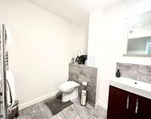 a white bathroom with a toilet and a sink at Home from Homes in Bedford