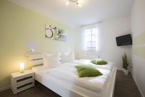 ein weißes Schlafzimmer mit einem großen weißen Bett mit grünen Kissen in der Unterkunft Residenz am Balmer See - BS 57 mit Wellnessbereich in Balm