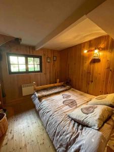 a large bed in a room with wooden walls at Chalet Familial in Matemale