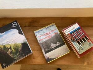 three books sitting on top of a wooden table at Dolce vita sur la colline de Turin in Revigliasco