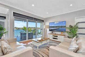 a living room with white furniture and a large window at Absolute Waterfront Lakehouse Fishing Point Waterfront Pool Jetty in Fishing Point