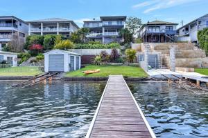 a dock in a body of water with houses at Absolute Waterfront Lakehouse Fishing Point Waterfront Pool Jetty in Fishing Point