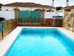 una piscina en un patio trasero con una valla de madera en Casa piscina Privada Vallada & Barbacoa A&C, en Chiclana de la Frontera