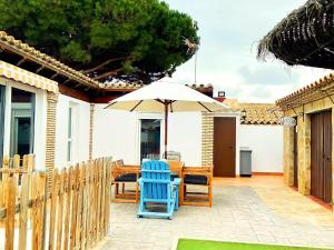 un patio con 2 sillas azules y una sombrilla en Casa piscina Privada Vallada & Barbacoa A&C, en Chiclana de la Frontera