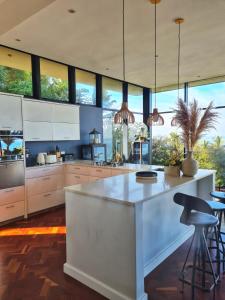 a kitchen with a large white island with bar stools at Designer Villa with solar power at epic eco-beach in Umdloti