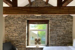 a bedroom with a stone wall and a window at Croft House Cottage in Halifax