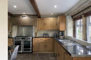 uma cozinha com armários de madeira e um forno com placa de fogão em Croft House Cottage em Halifax